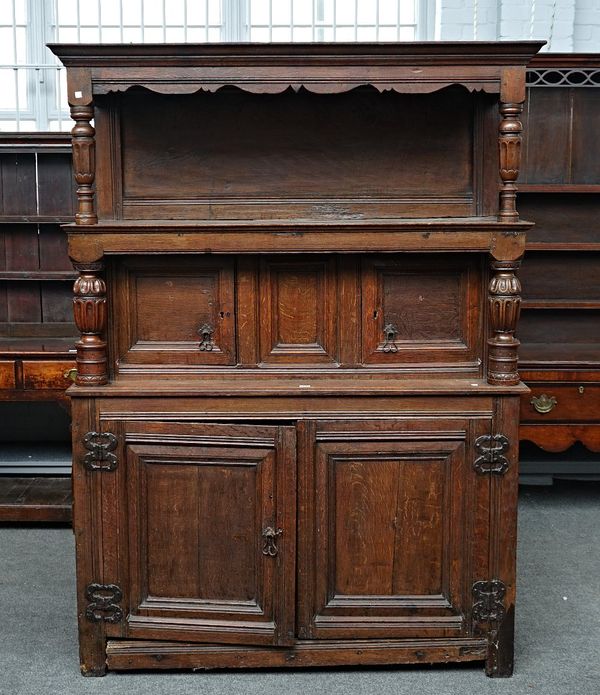 A 17th century oak court cupboard/Tridarn, the open upper tier over two pairs of panelled covers divided by turned supports, 145cm wide x 195cm...