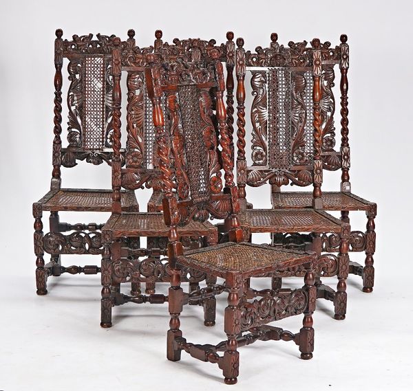 A set of six 17th century style carved oak and cane dining chairs with carved figural crests on turned supports, 47cm wide x 118cm high.