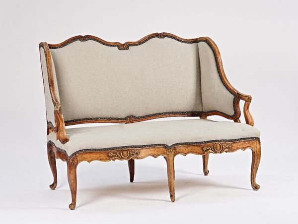 An 18th century French high wingback carved walnut framed sofa on scroll supports, 143cm wide x 104cm high.