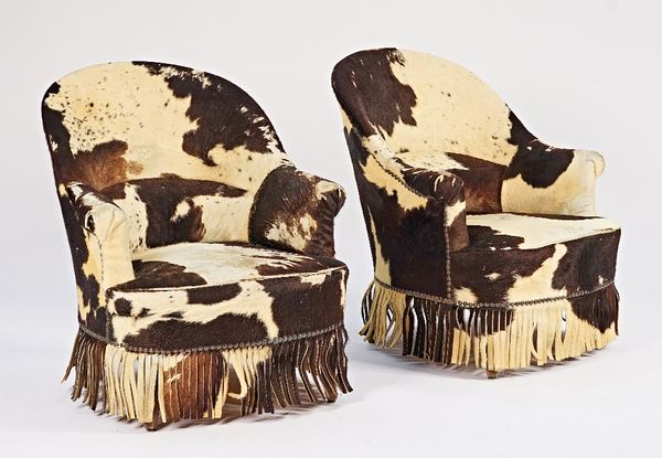 A pair of early 20th century French, later cow hide upholstered, tub back easy armchairs on splayed supports, 75cm wide x 82cm high (2).