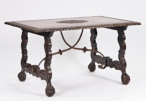 A 19th century Spanish walnut centre table, the rectangular top with carved crest on shaped supports united by wrought iron stretcher on claw and ball...