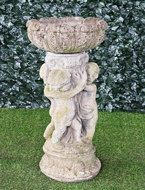 A reconstituted stone bird bath, with circular reservoir on cherub base, 47cm diameter x 92cm high.