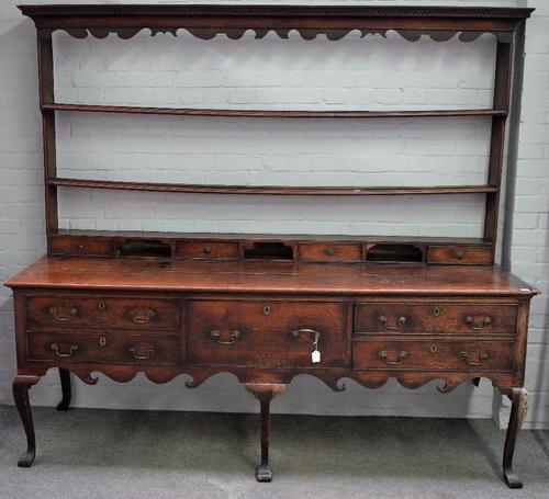 A George III oak dresser, the open back with four small drawers, the base with a deep drawer flanked by four short drawers on cabriole legs