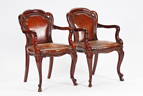 A pair of Victorian mahogany framed brown leather upholstered open armchairs