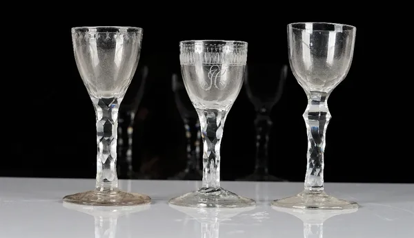 Three facet stemmed wine glasses, late 18th century, one engraved with the initial `H' beneath a foliate border, another engraved with an OXO border,...