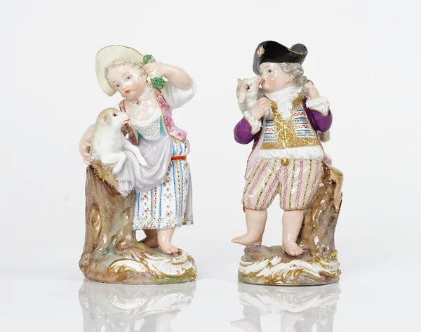 A pair of Meissen figures of a shepherd boy and girl, late 19th century, the boy carrying a lamb across his shoulder, the girl holding a lamb across...