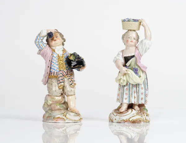 Two Meissen figures of vintners, late 19th century, the first modelled as a boy holding a hat full of grapes under his left arm and a bunch of grapes...
