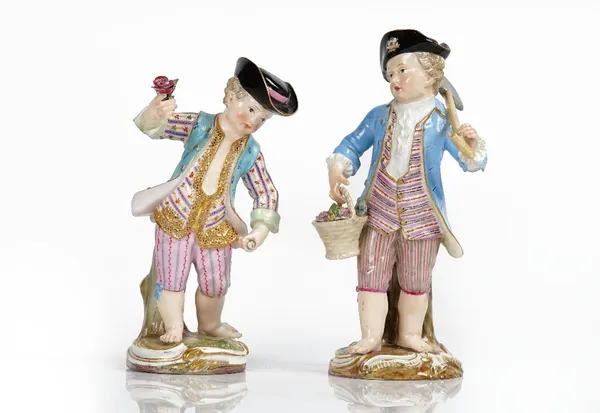 Two Meissen figures of boy gardeners, late 19th, one modelled carrying a rake and basket of flowers, the other with a sickle and flower posy, (a.f),...