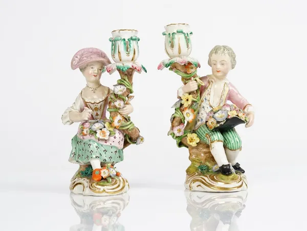 A pair of Derby porcelain candlestick figures, circa 1820-30, modelled as a boy and girl seated with flowers beside a flower encrusted column...