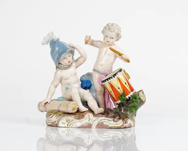 A Meissen outside decorated group emblematic of War, late 19th century, modelled as two putti with martial trophies, one wearing a helmet, the other...