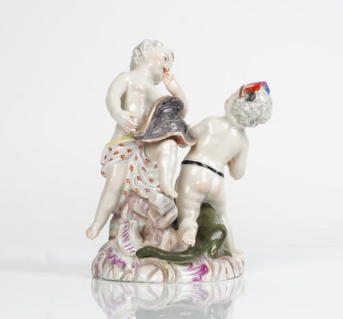 A German porcelain group of two putti, probably Meissen, emblematic of America and Europe, the former seated on the back of an alligator wearing a...