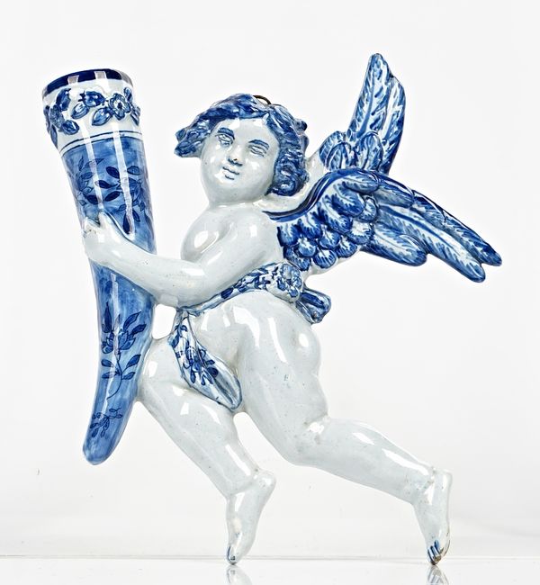 A Continental blue and white tin glazed earthenware wall pocket, possibly Samson, late 19th century, modelled as a cherub holding a cornucopia...