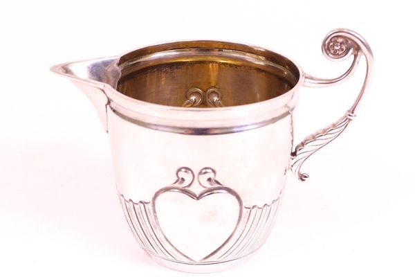 A late Victorian silver milk jug, with a foliate capped scrolling handle and decorated with two heart shaped cartouches, otherwise with spiral bands,...