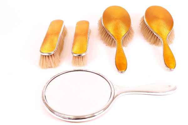 A silver and yellowy/orange enamelled five piece lady's dressing set, comprising; a hand mirror, two hairbrushes and two clothes brushes, four pieces...