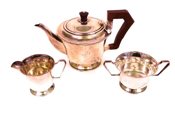 A silver three piece tea set, comprising; a teapot, with brown composition fittings, a twin handled sugar bowl and a milk jug, Birmingham 1947,...