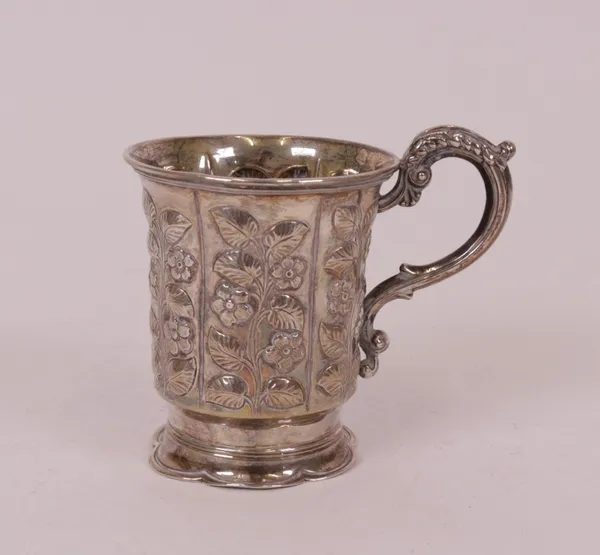 A Victorian silver christening mug, the body panels decorated with floral sprays, with a scrolling handle and raised on a shaped hexafoil foot,...