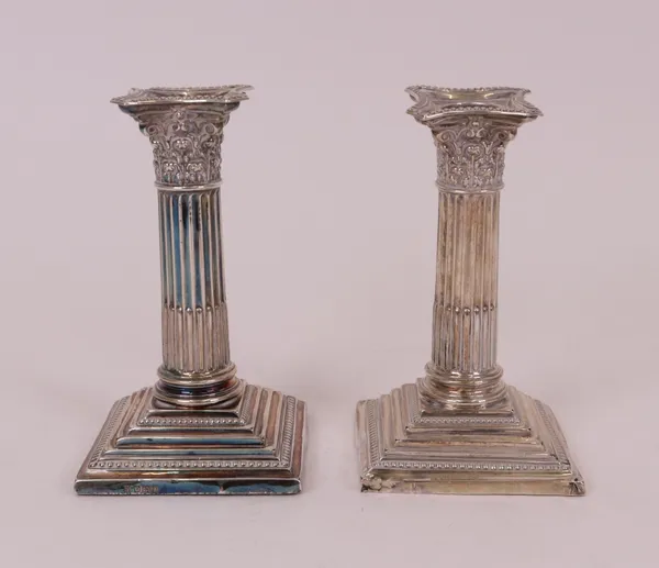 A pair of silver candlesticks, each designed as a Corinthian column, raised on a stepped square base (loaded), height 13.5cm, one hallmarked...