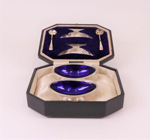 A pair of silver salts, each of boat shaped form, having flowerhead motifs to the rims, Birmingham 1908, with two blue glass liners and a pair of Old...