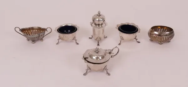 A group of silver condiments, comprising; a four piece condiment set, each piece of shaped circular form, raised on three feet, Birmingham 1908, with...