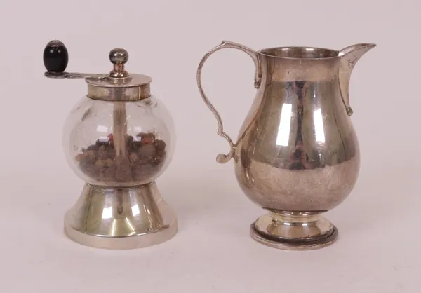 A silver cream jug and a pepper mill