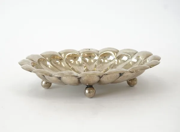 A European shaped oval dish, of panelled form, radiating from the centre within a lobed rim, raised on four spherical feet, 29cm across, weight 376 gms.   7112