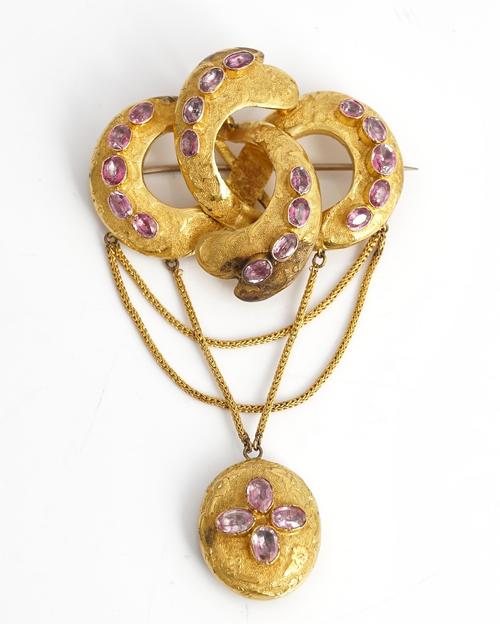 A Victorian foil backed pink gemstone set brooch, of four section entwined design, the front with an oval pendant locket, glazed at the back...
