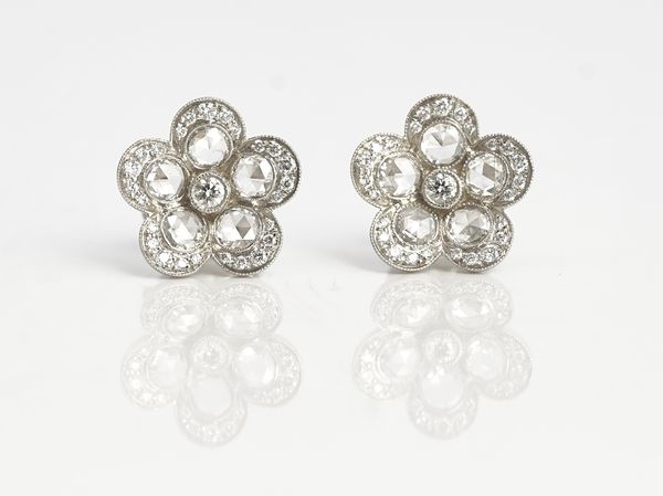 A Tiffany & Co pair of platinum and diamond earstuds, each designed as a flowerhead, mounted with the principal circular cut diamond at the centre,...