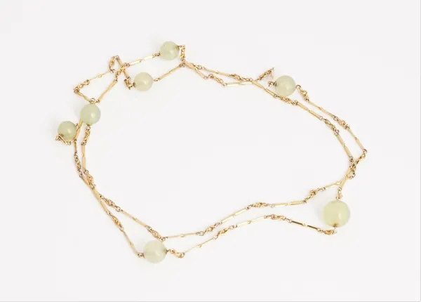 A gold and pale green gemstone bead necklace, the bar and twist link chain spaced with seven pale green gemstone beads at intervals, detailed 9 CT,...