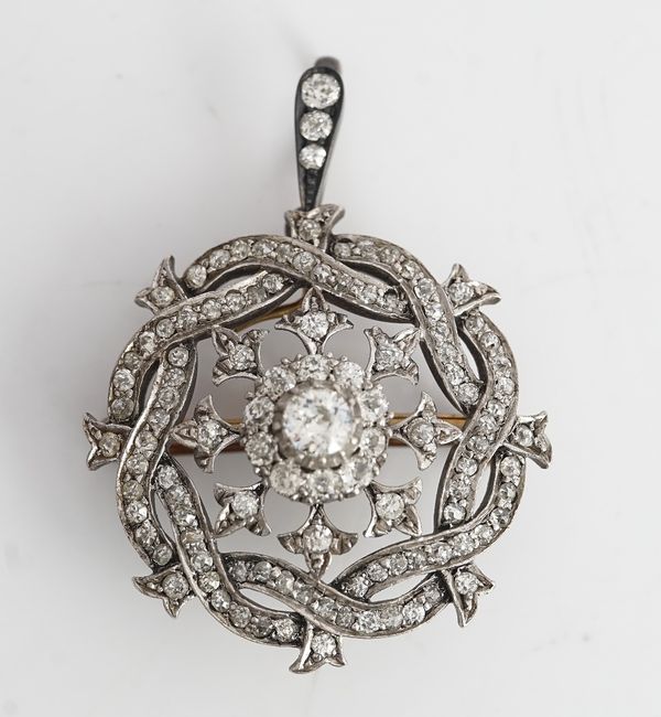 A diamond pendant brooch, circa 1900, of shaped circular form, the centre cluster mounted with the principal cushion shaped diamond in a surround of...