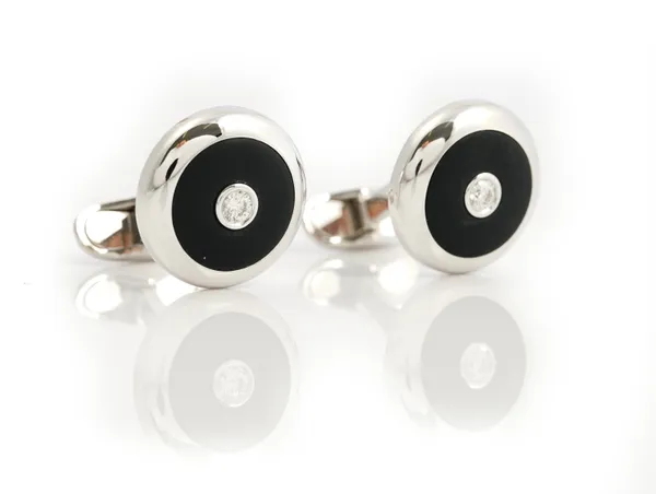 A pair of white gold, diamond and black onyx dress cufflinks, each circular front mounted with a circular cut diamond on a matt finish black onyx...