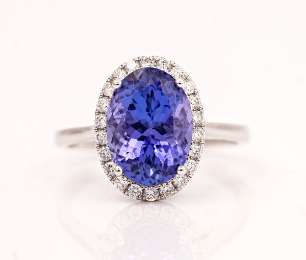 A white gold, tanzanite and diamond oval cluster ring, claw set with the oval cut tanzanite in a surround of circular cut diamonds, detailed (18ct...