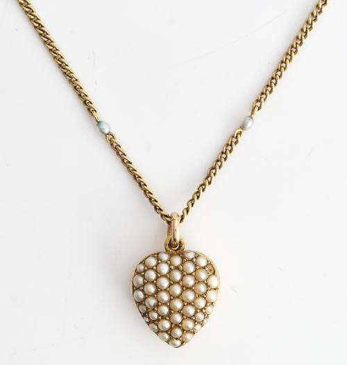 A gold and seed pearl set heart shaped pendant locket, the front pave set with seed pearls, the back glazed with a locket compartment and detailed 15...