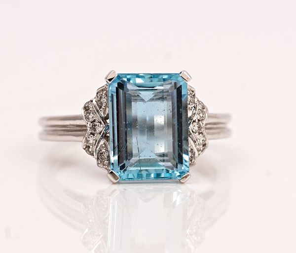 An 18ct white gold, aquamarine and diamond ring, claw set with the rectangular step cut aquamarine between circular cut diamond set shoulders, with...