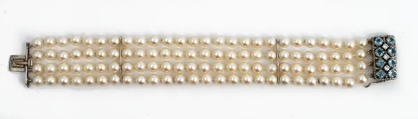 A four row bracelet of cultured pearls, on a white gold, diamond and pale blue gemstone set rectangular clasp, mounted with three circular cut...