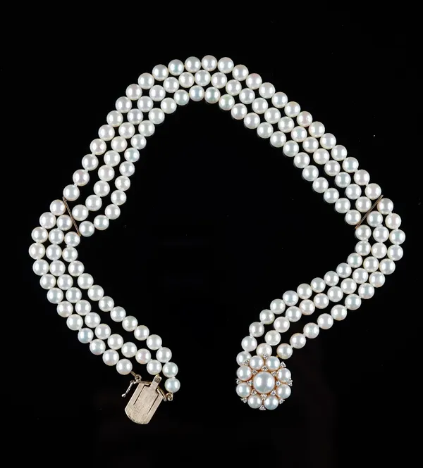 A three row necklace of cultured pearls, on a 9ct gold cultured pearl and diamond cluster clasp, length including clasp 32cm.