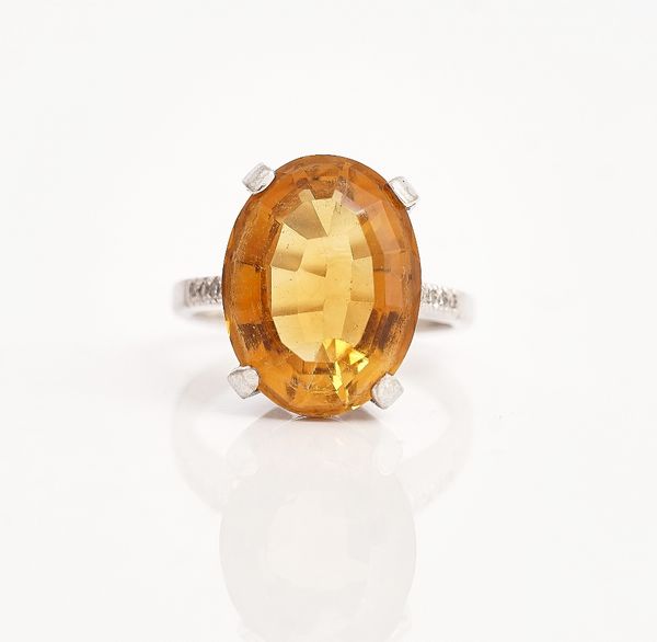An 18ct white gold, citrine and diamond ring, claw set with the oval cut citrine between diamond set four stone shoulders,