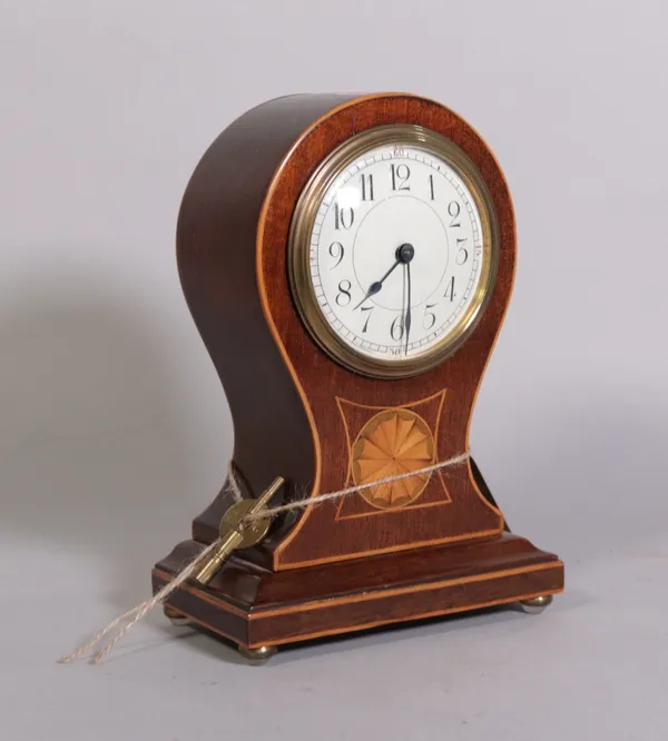 An Edwardian inlaid mahogany balloon shaped mantel clock on brass bun feet