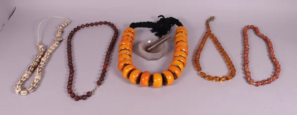 A composite amber bead necklace, four carved beaded necklaces and an agate pestle and mortar (6)