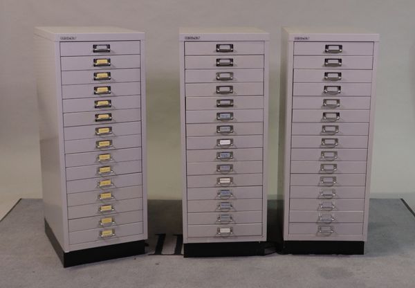 ‘Bisley’, a group of three grey painted metal filing cabinets with fifteen short drawers.