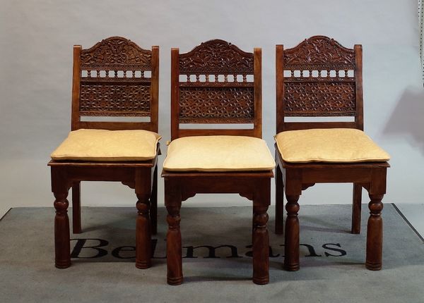 A set of eight Indian hardwood dining chairs with floral trellis carved back on turned supports,