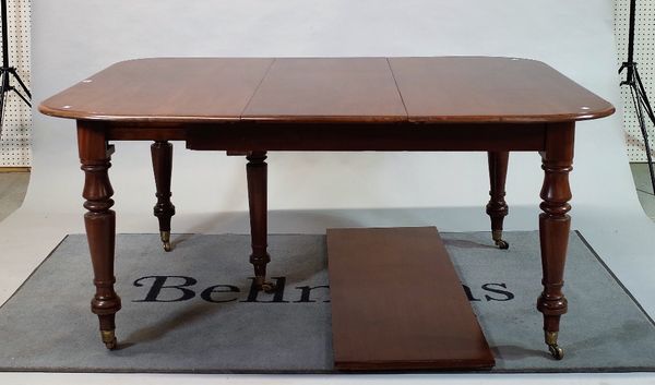 A Victorian mahogany extending dining table with two extra leaves on turned supports,