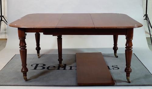 A Victorian mahogany extending dining table with two extra leaves on turned supports,