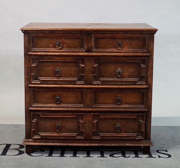 A Charles II style oak desk of two short and three long geometric moulded drawers