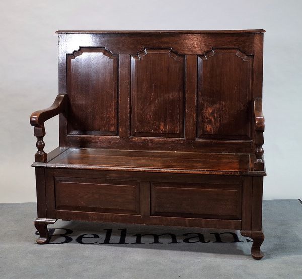 An 18th Century oak settle with panelled back over lift top seat