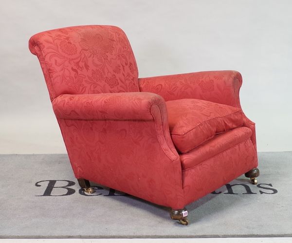 An early 20th century red upholstered easy armchair on bun feet