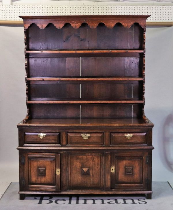 A late 19th century oak dresser with three tier plate rack over three frieze drawers and panelled cupboard base