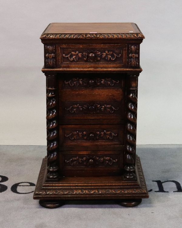 An 18th century style oak bedside table with three drawers flanked by spiral columns on pad feet