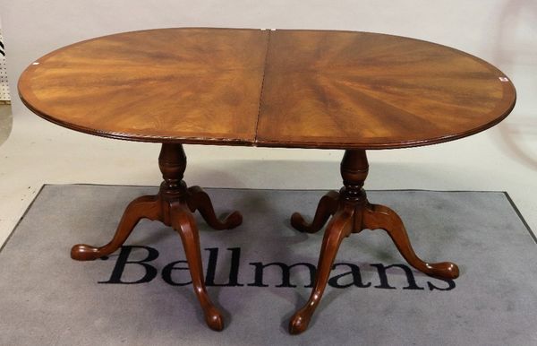 A modern mahogany and yew wood banded 'D' end extending dining table on baluster column and three downswept supports with one extra leaf