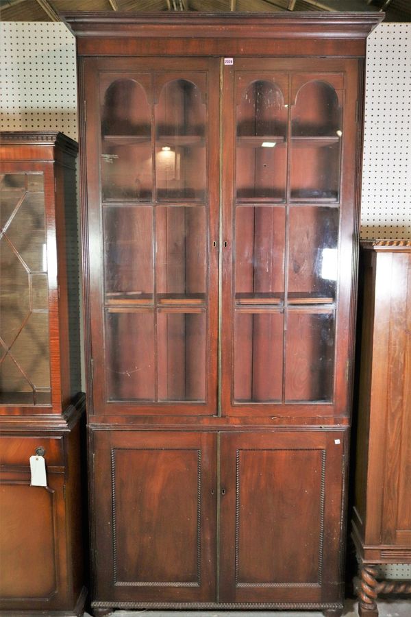 A late William IV mahogany bookcase cabinet with arched glazed doors over cupboard base