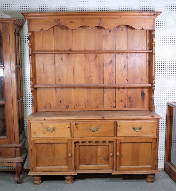 A late Victorian pine kitchen dresser with a two tier plate rack over three short drawers on turned supports